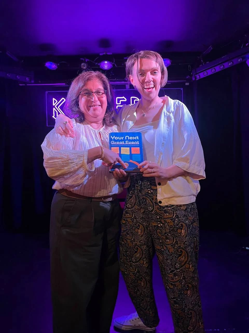 Two people holding Your Next Great Event at an evening gathering